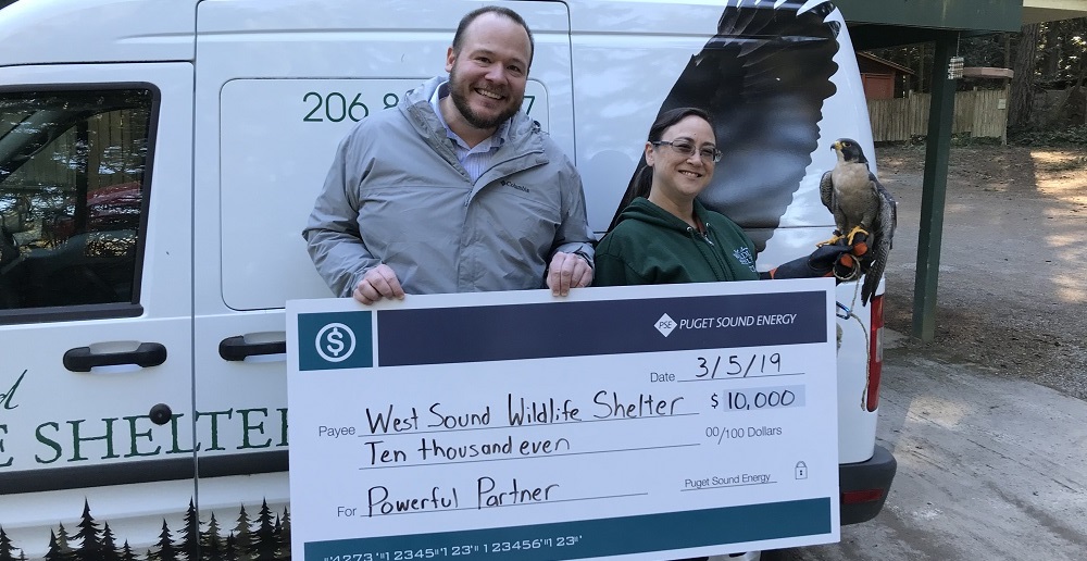 PSE outreach lead pictured in front of a check for West Sound Wildlife Shelter
